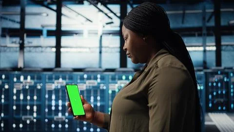 Manager using app on chroma key phone to check server farm energy consumption Foto stock