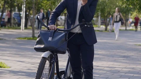 Manager using eco-transport and talking by mobile phone in park Vidéo 120665922