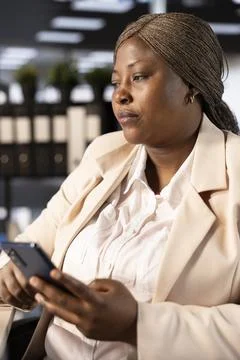 Manager using phone to send messages in office Stockfoto's