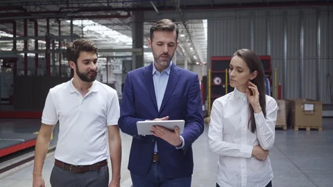 Manager walking in factory with two engineers explaining and showing on table Stock Footage 108446125