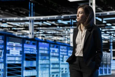 Manager walking through server room rows lined with storage infrastructure rigs Stock Photos