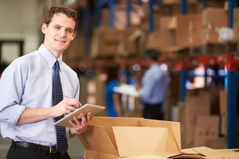 Manager in warehouse checking boxes using digital tablet Foto stock