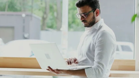 Manager working on his laptop and standing near window Stock Footage 112987509