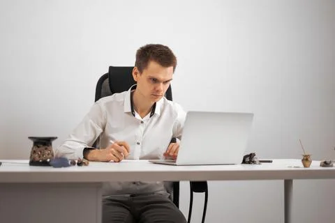 The manager works on a computer sitting at a white desk in the office Stock Photos