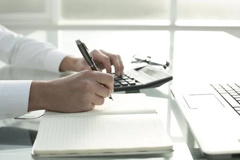 The manager works in the office, keeps notes in a notebook and counts on a Stock Photos