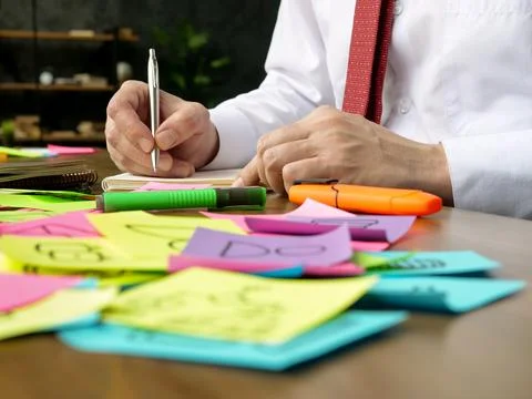 The manager works with papers at the table. Lots of multicolored stickers. Stock Photos
