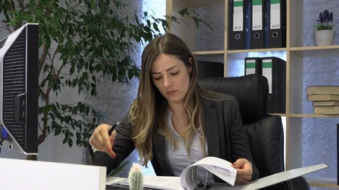 The manager writes on the computer and checks the documentation at the table. Vídeos de archivo 108387519