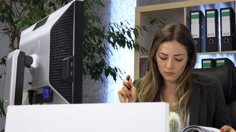 The manager writes on the computer and checks the documentation at the table. 動画素材 108424316