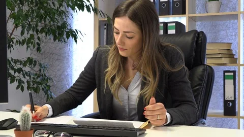 The manager writes on the computer and checks the documentation at the table. Видео 108649066