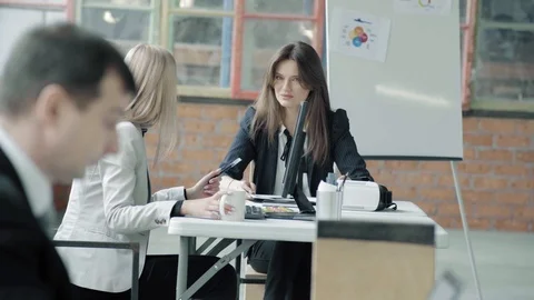 Managers are sitting at the table and chatting. A young employee walks into the Stock Footage 124546745