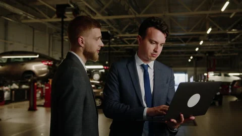 Managers are standing with laptop while filling out application for car repairs Stock Footage 256074146