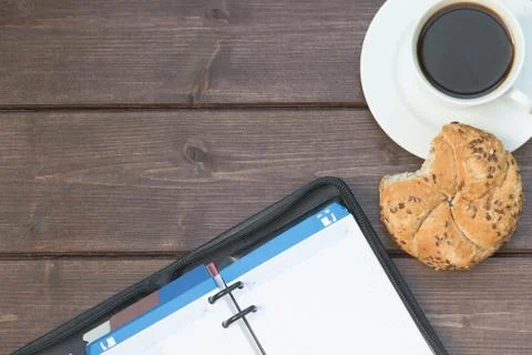 Managers diary and coffee cup on the wooden desk 写真素材