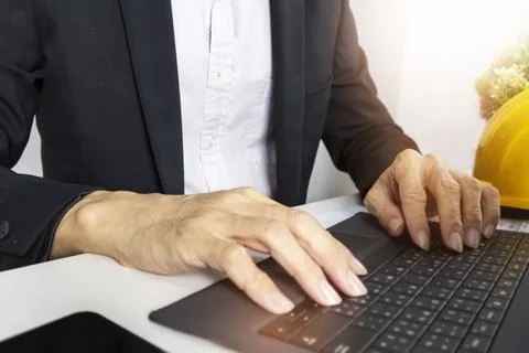 Managers engineer work and type data into project management notebooks. Stock Photos