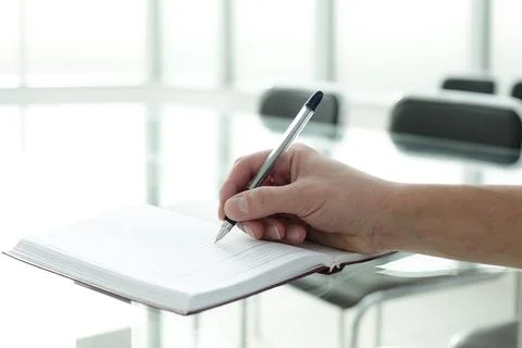 Manager's hand writes in notebook in office space Stock Photos
