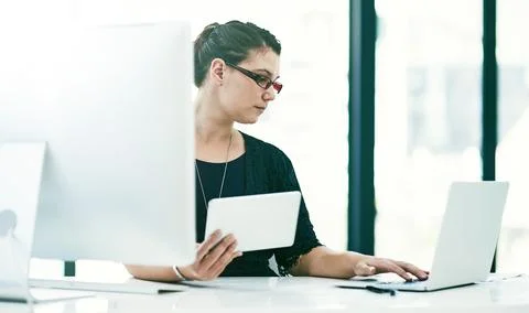 Managing her business processes on multiple devices. a young businesswoman Stock Photos