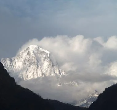 Manaslu mountain with snowy peaks in clouds on sunny bright day in Nepal. Stock Photos