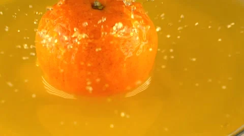 Mandarin hitting orange juice surface slow motion shot Stock Footage 61134664