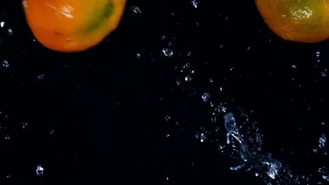 Mandarines and red oranges are falling and splashing in extreme slow motion. 库存影片 74387705