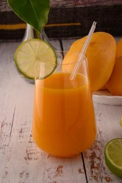 Mango beverage close up with lime slice on white vintage wooden table Stock Photos