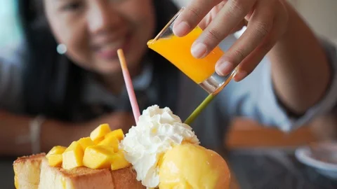 Mango bread toast ice-cream with woman pouring fruit sauce on whipping Stock Footage 94138067