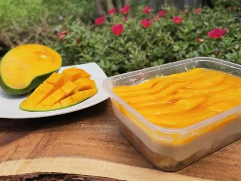Mango Cheese Cake in Container and Peeled Mango on Wooden Board  Stock Photos