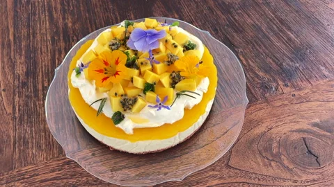 Mango cheesecake topped with cream, fresh fruit and colourful flowers Stock Footage 278503679