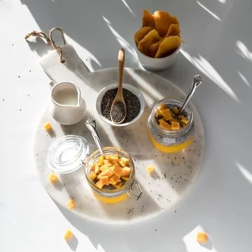 Mango chia pudding snacks on a white marble slab in shadowy bright sunlight Stock Photos