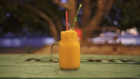 A mango cocktail stands on a table Stock Footage 155797496