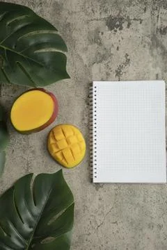 Mango with cubes and empty notebook paper on marble surface Stock Photos