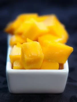 Mango Cubes on a white dish dark Background Foto stock