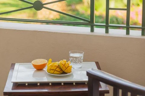 Mango cut in half and orange with a cold drink on a tray on the hotel balcony on Stock Photos