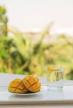 Mango cut in half with a cold drink on white tray on the hotel balcony on Stock Photos
