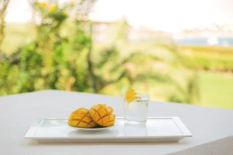 Mango cut in half with a cold drink on white tray on the hotel balcony on Stock Photos