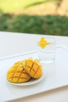 Mango cut in half with a cold drink on white tray on the hotel balcony on Stock Photos