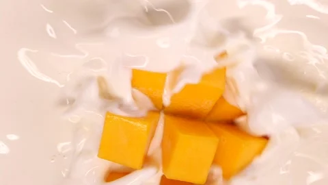 Mango falling and splashing into cream, milk or yoghurt in super slow motion. Stock Footage 155200988