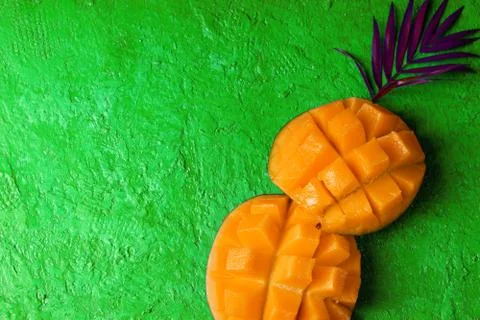 Mango in the form of a palm trunk and pink palm leaf on a bright green backgr Stock Photos