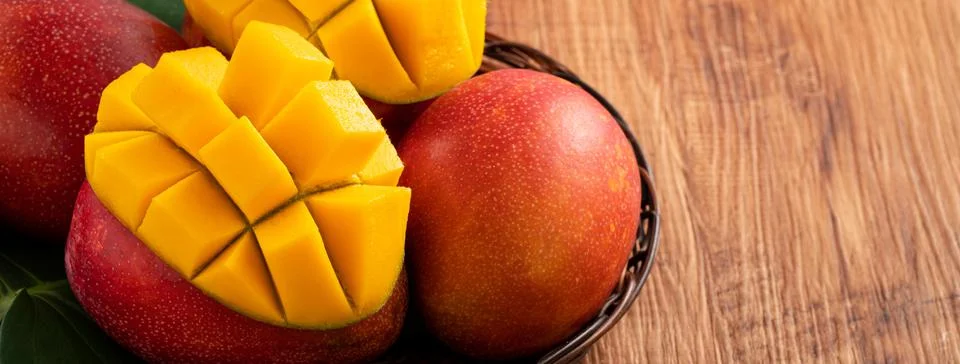 Mango. Fresh mango fruit with leaves over dark wooden table background. Stock Photos