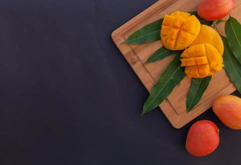 Mango fruit and mango cubes on the wooden cutting board. Tropical fruit concept Stock Photos