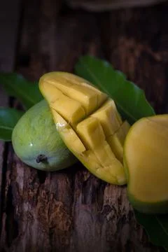 Mango fruit and mango cubes on the wooden table Stock Photos