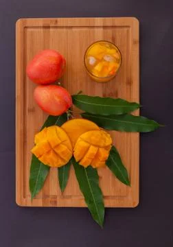 Mango fruit and mango drink on the wooden cutting board. Tropical fruit. Stock Photos
