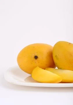 Mango fruit in basket with slice on white background Stock Photos