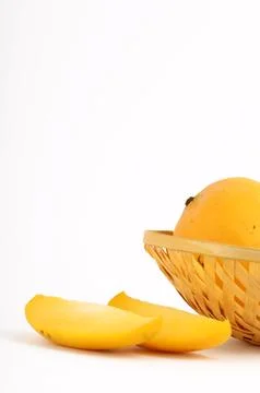 Mango fruit in basket with slice on white background Stock Photos