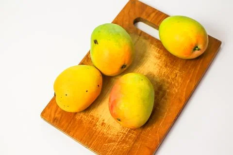Mango fruit on cutting board isolated on white background, whole ripe yellow  Stock Photos