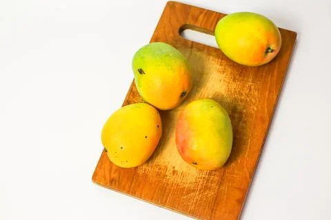 Mango fruit on cutting board isolated on white background, whole ripe yellow  Stock Photos