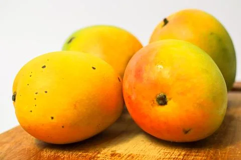 Mango fruit on cutting board isolated on white background, whole ripe yellow  Stock Photos