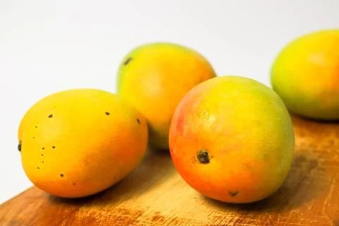 Mango fruit on cutting board isolated on white background, whole ripe yellow  Stock Photos