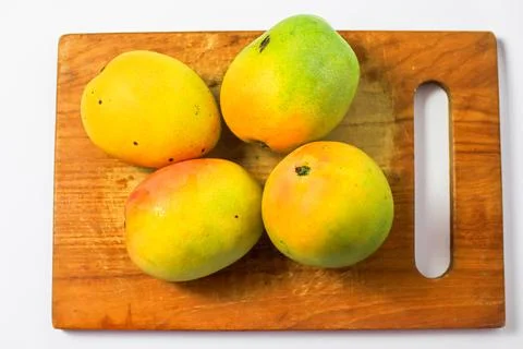Mango fruit on cutting board isolated on white background, whole ripe yellow  Stock Photos