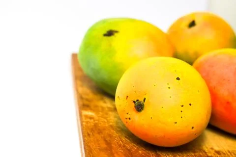 Mango fruit on cutting board isolated on white background, whole ripe yellow  Stock Photos