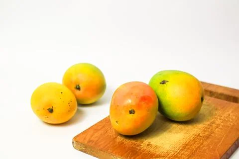 Mango fruit on cutting board isolated on white background, whole ripe yellow  Stock Photos