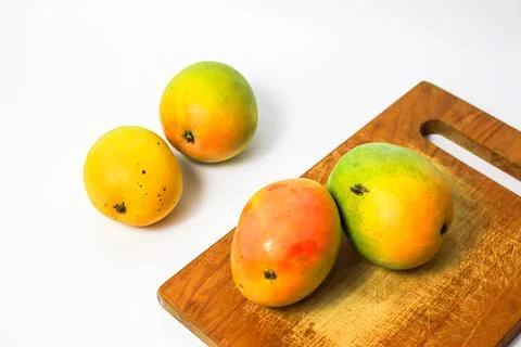 Mango fruit on cutting board isolated on white background, whole ripe yellow  Stock Photos